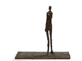 statue d'un homme debout sur un socle en bois, sur fond blanc