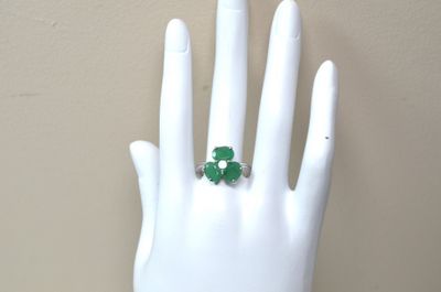 une main blanche portant une bague verte au doigt