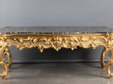 an ornately carved table with a marble top on a grey floor