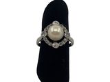 an image of a pearl and diamond ring on a black velvet ring holder
