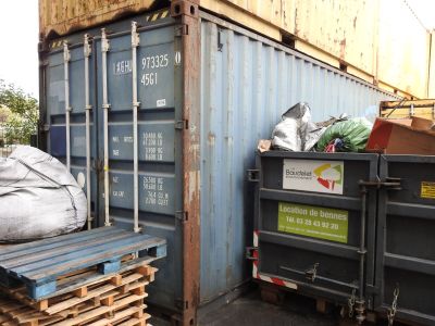 a large blue container sitting next to a pile of wood