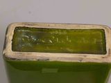 a green vase with a white base on a table