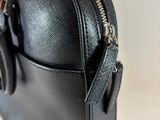 a hand holding a black purse with a zipper on it