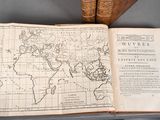 map of the world in a book on a table next to two old books