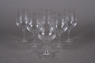 six empty wine glasses lined up on a table