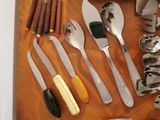many different types of silverware on a wooden table