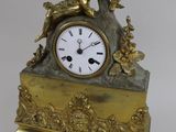 a gold clock with a man playing a flute on it