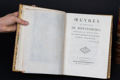 quelqu'un tient un livre à la main près d'une pile de livres