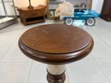 un petit tabouret avec une assise en bois posé sur un sol carrelé
