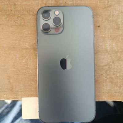 Un iPhone est posé sur une table en bois, à côté d'un jean bleu.