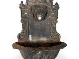 une vieille fontaine en métal surmontée d'une tête de lion