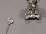 une assiette en argent avec une cuillère et un repose-cuillère posés sur une table