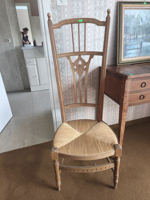 Une chaise basse paillée à dossier ajouré.