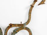pair of metal sculptures of two snakes on wheels against a white wall