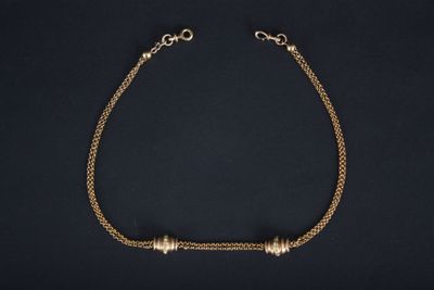 un bracelet en chaîne dorée orné de trois perles sur fond noir