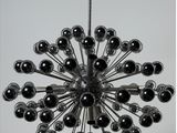 a black and white photo of a chandelier with chrome balls