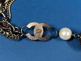 a close up of a chain bracelet with a key and a pearl bead