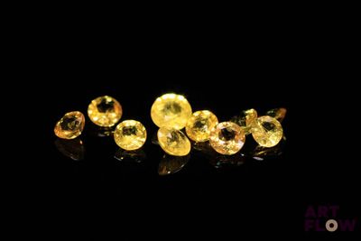 a group of yellow sapphires on a black surface