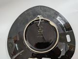 a black plate with a gold rim on a white table