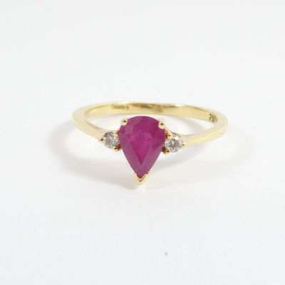 a close up of a yellow gold ring with a pear shaped ruby stone