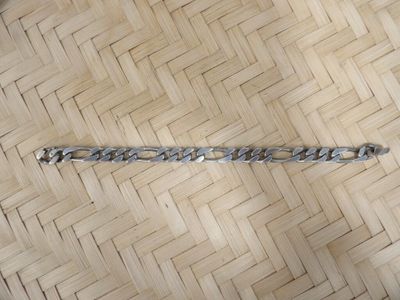 a silver bracelet that is on a wooden floor