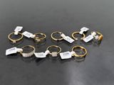 six gold and silver rings with tags on them on a black surface