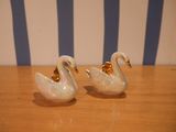 pair of white and gold swan salt and pepper shakers on a wooden table