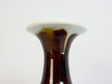 un vase brun posé sur une table à fond blanc