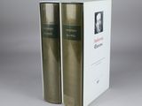 two books are sitting on top of each other in front of a white box