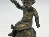 statue en bronze représentant un garçon assis sur un rocher, tenant un oiseau dans la main