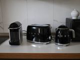 a black toaster, a coffee maker, and a toaster on a counter
