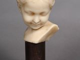 a white marble bust of a boy on a wooden base