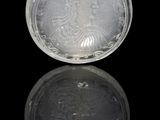 flacon à priser en verre argenté et bleu posé sur une surface réfléchissante