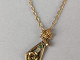 a gold plated necklace with a green glass bottle on a gold chain