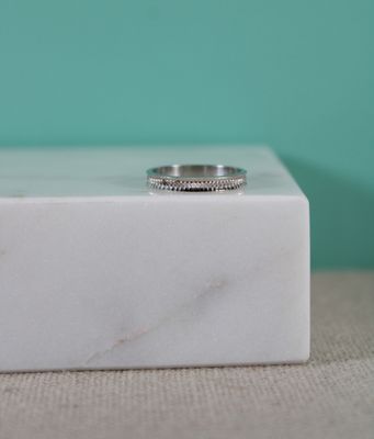 un gros plan d'une bague posée sur un bloc de marbre, sur une table