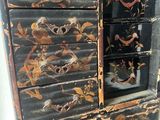 a black and gold chest of drawers with flowers on it