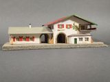 a small model of a house with red shutters on the windows