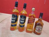 trois bouteilles de whisky posées sur une table près d'un mur rouge