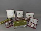 several silver spoons and spoon rest in a case on a table