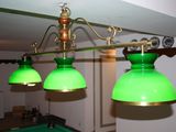three green lamps hanging from the ceiling above a pool table