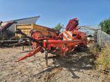 un semi-remorque rouge garé sur un terrain en terre battue à côté d'un bâtiment