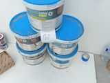 several buckets of paint sitting on top of a table next to a wall