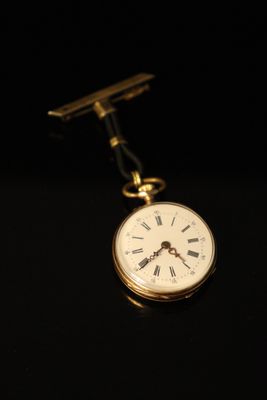 an old pocket watch with a tie bar on a black background