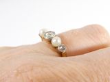 a close up of a person ' s hand with a pearl and diamond ring