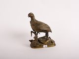 statue en bronze représentant un oiseau posé sur un rocher, sur fond blanc