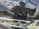 a reflection of a man holding a fish on the hood of a car