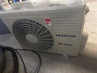 un petit climatiseur posé par terre à côté d'un tuyau d'arrosage