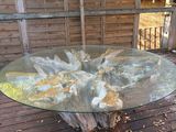 une table en verre sur une terrasse en bois, avec des feuilles par terre