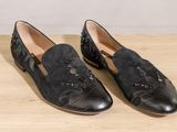 the black loafer is on a wooden surface with a white background