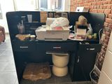 a desk with a printer and a trash can in the corner